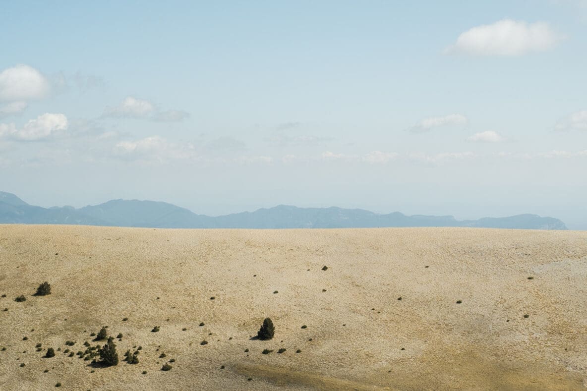 The view towards the range of the Pyrenees from the rolling foothills of Prat de Compte during the summer.